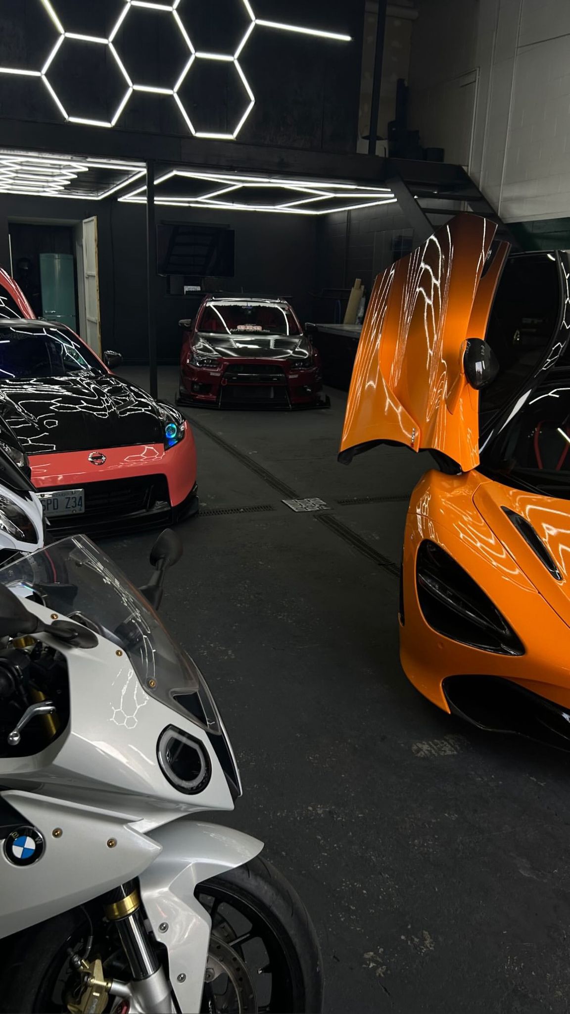 Vehicles and bike inside SESTO tint and styling bay with hex lighting overhead